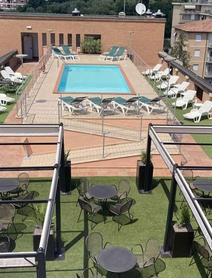 Terrazza con piscina, sdraio e tavolini, atmosfera estiva e rilassante.