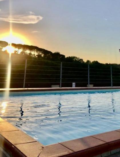 Piscine au coucher du soleil, lumière dorée sur l'eau, ambiance sereine et relaxante.