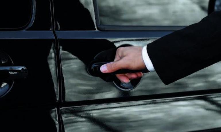 Mano apre la portiera di un'auto nera.