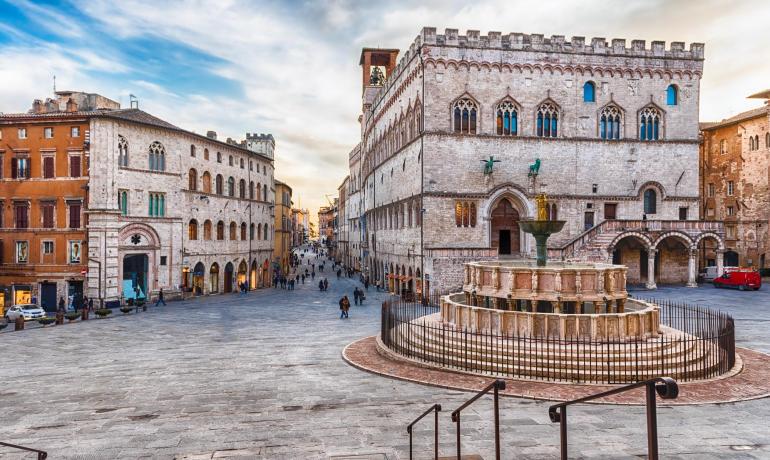 Piazza storica con fontana e palazzo medievale a Perugia.