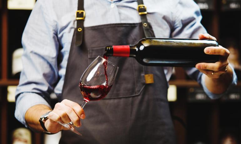 Sommelier versa vino rosso in un calice.