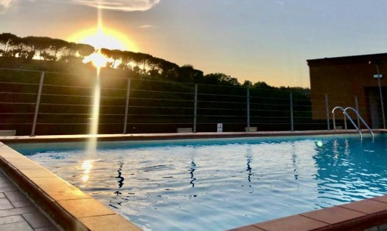 Piscina al tramonto con vista sugli alberi.