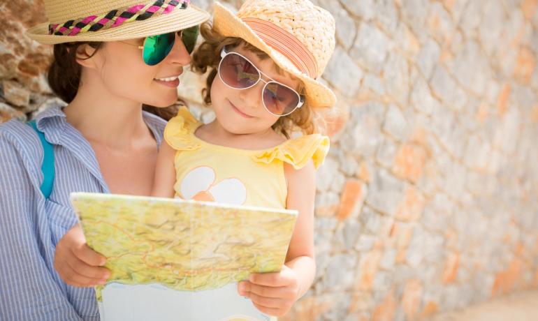 Madre e figlia leggono una mappa, indossando cappelli e occhiali da sole.