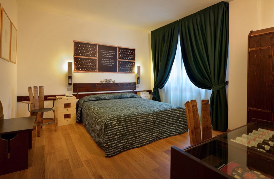 Camera d'albergo moderna con letto matrimoniale, finestra grande e decorazioni artistiche sulla parete.