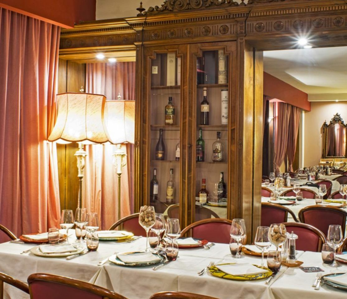 Ristorante elegante con arredi classici, luci soffuse e tavoli apparecchiati con cura.