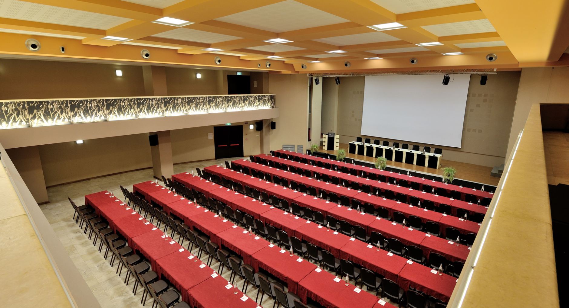 Auditorium con sedie rosse e palco, ideale per conferenze e eventi musicali.