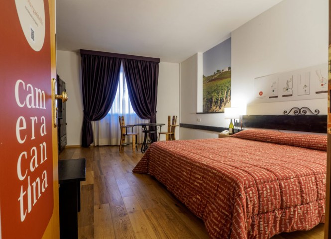 Camera accogliente con letto matrimoniale, arredamento rustico e decorazioni a tema vinicolo.