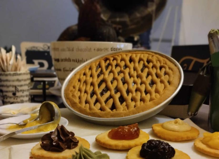 Dolci colorati e profumati, una crostata e biscotti con creme e marmellate.