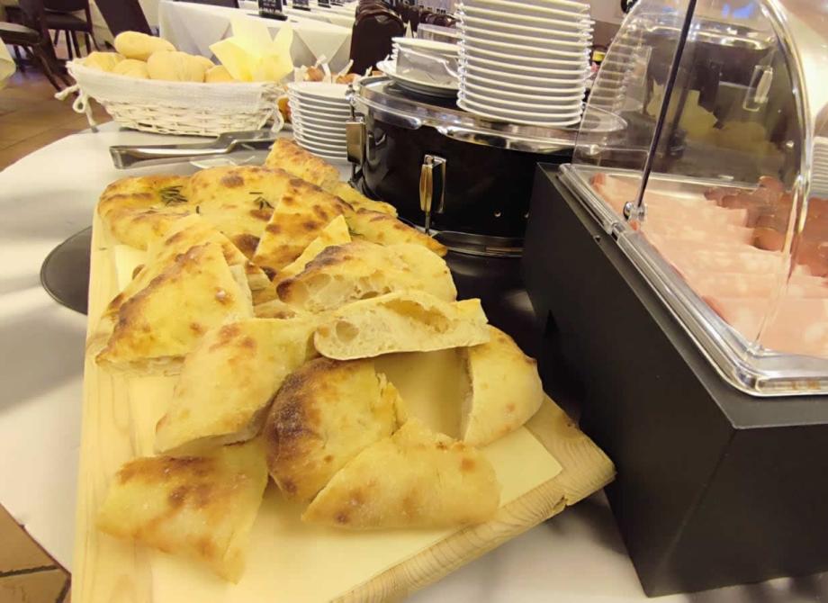 Buffet con focaccia, affettati e pane, perfetto per un pasto conviviale.