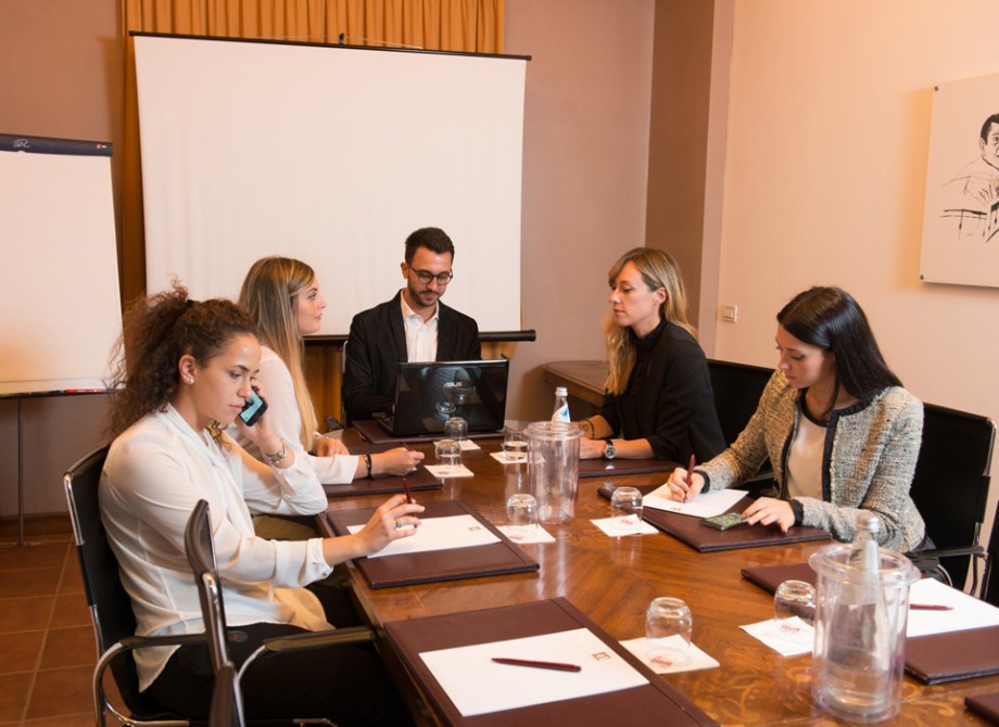 Riunione intensa, cinque persone concentrate su appunti e discussioni.