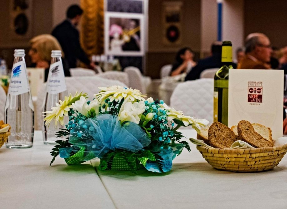 Tavola elegante con fiori, vino e pane in un'atmosfera conviviale.