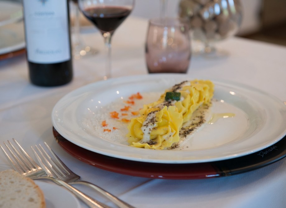 Piatto raffinato di pasta fresca con vino rosso, eleganza e sapori intensi.