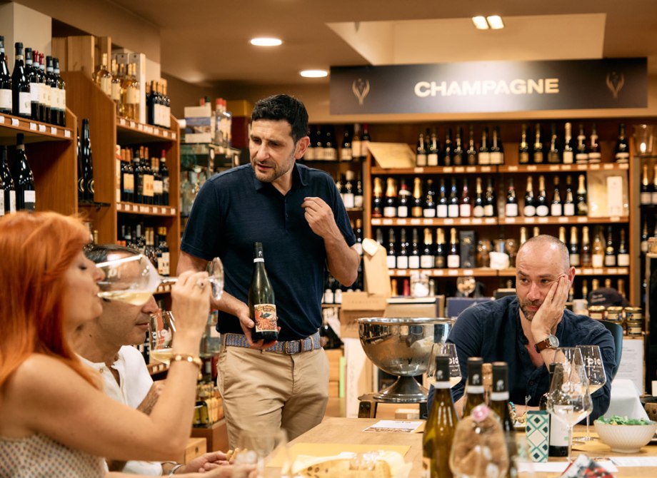 Degustazione di vini in enoteca con gruppo di persone e bottiglie esposte.