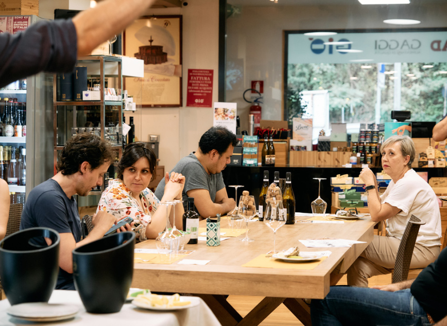 Persone sedute a un tavolo degustano vino in un ambiente accogliente.