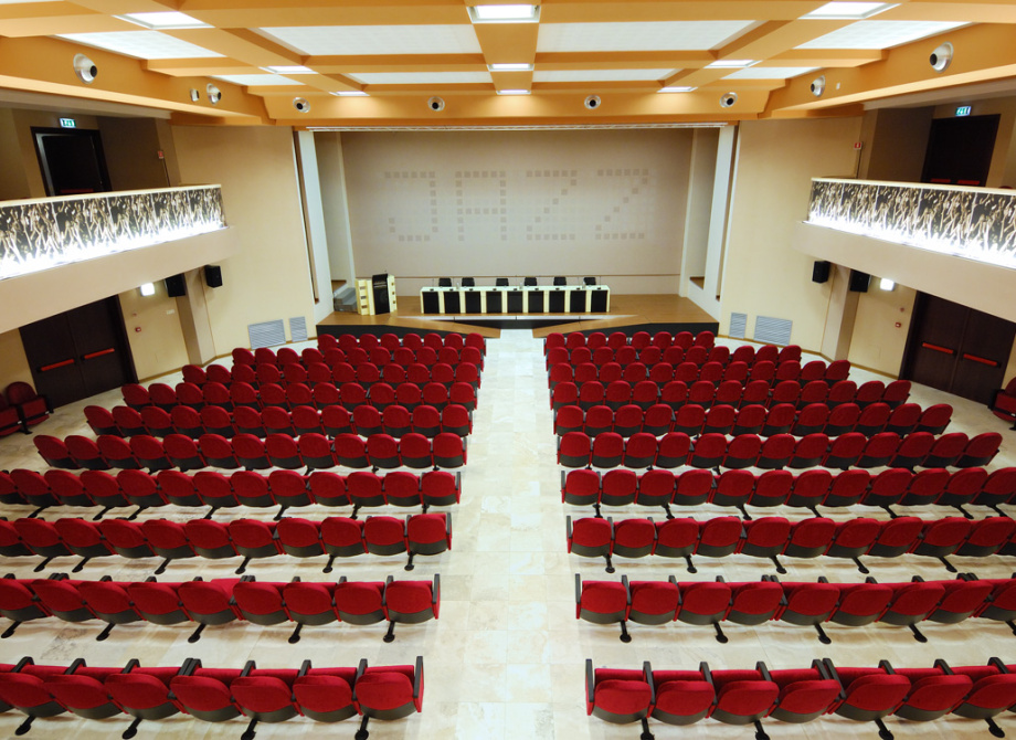 Auditorium con sedie rosse, palco e scritta 'JAZZ' sullo sfondo.