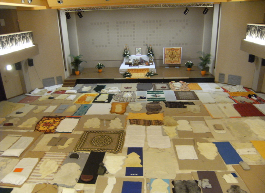 Sala con tappeti e coperte disposte per meditazione o evento spirituale.