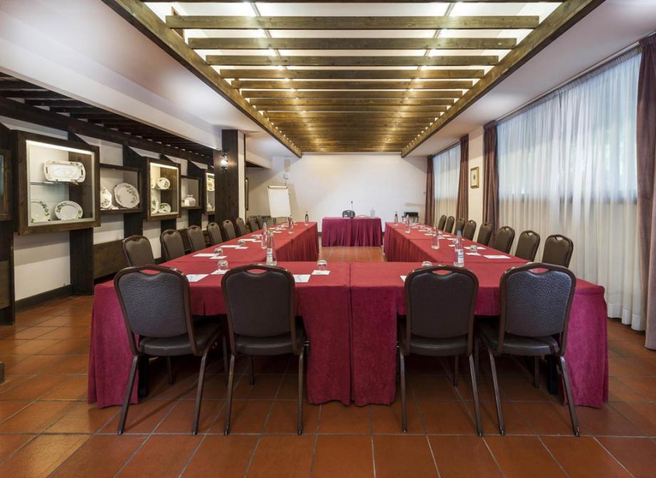 Sala conferenze con tavoli a U, sedie e decorazioni in ceramica esposte.