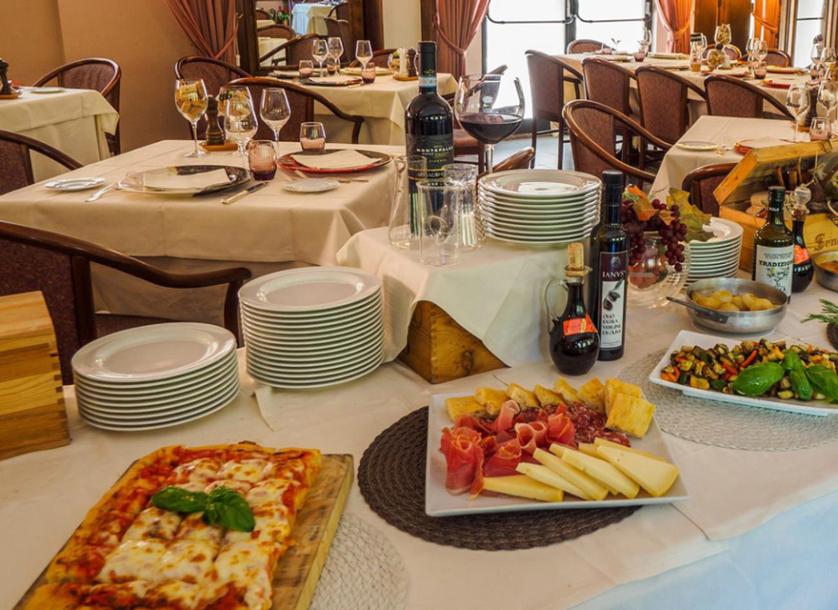 Tavolo imbandito con piatti italiani, vino e affettatrice in un ristorante elegante.