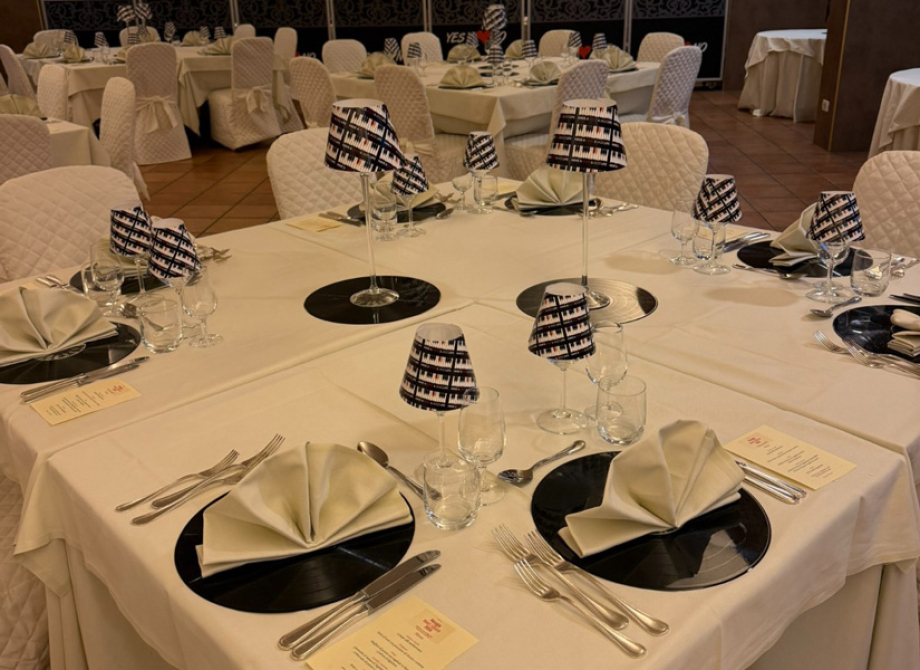 Sala da pranzo elegante con decorazioni musicali e tovaglioli piegati su piatti neri.