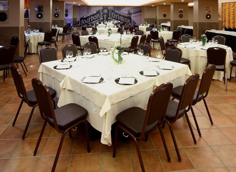 Sala da pranzo elegante con tavoli apparecchiati e decorazioni raffinate, pronta per un evento.