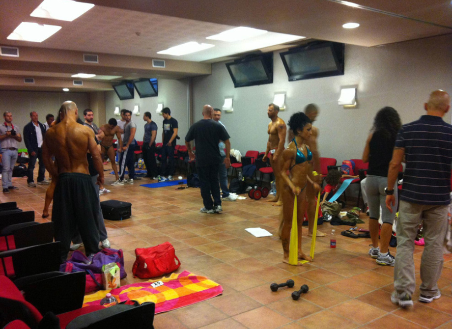 Persone in preparazione per una competizione di bodybuilding in una sala.